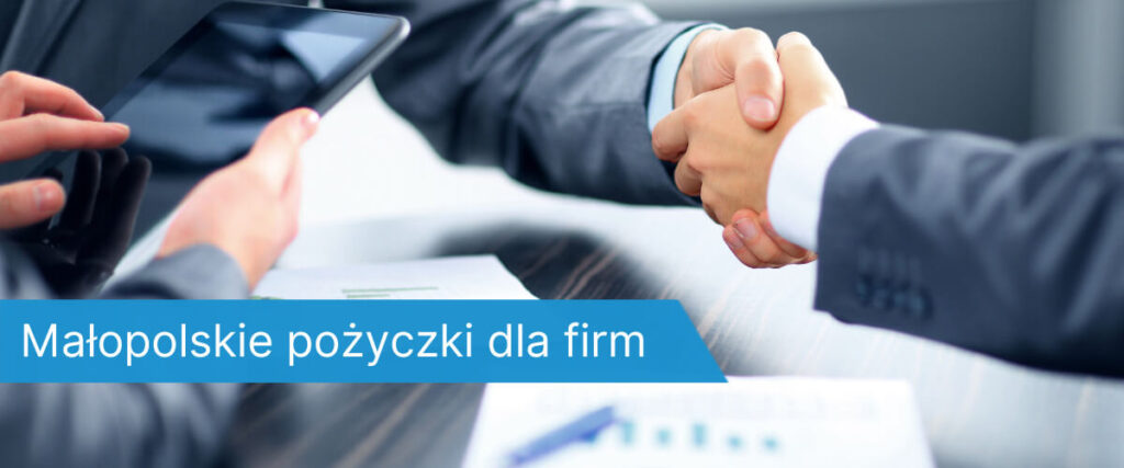 Dwóch mężczyzn w garniturach podaje sobie ręce nad dokumentami i tabletem podczas spotkania biznesowego